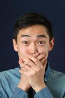 verrast jonge Aziatische man die zijn mond met palmen