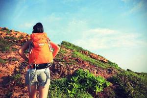 jonge vrouw backpacker klimmen naar bergtop foto