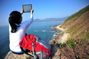 wandelende vrouw gebruik digitale tablet aan zee foto