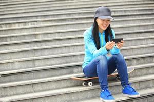 jonge vrouw skateboarder gebruiken haar mobiele telefoon op trappen zitten