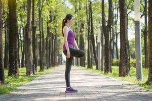 sportieve jonge Aziatische vrouw die zich uitstrekt na joggen in het bos foto