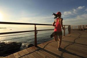gezonde levensstijl sport vrouw draait op houten promenade zonsopgang aan zee foto