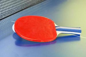 rood knuppel, tennis bal Aan blauw ping pong tafel foto