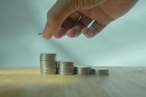 Mens hand- zetten geld naar munten stack Aan houten tafel met wazig achtergrond besparing concept foto