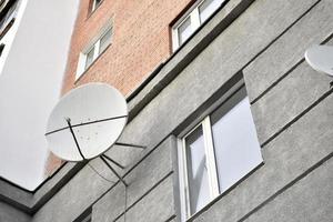 satelliet schotel Aan een grijs gebouw detailopname. een parabolisch antenne Aan de muur. foto