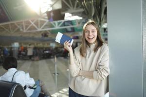 portret van gelukkig jong vrouw Holding paspoort en instappen voorbij gaan aan Bij luchthaven foto