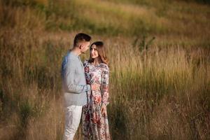 jong koppel rusten in de natuur in een veld. koppel bij zonsondergang foto