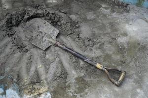 een Schep is gebruikt net zo een timmerwerk gereedschap naar lepel uit cement en zand. foto