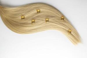 een haar- zorg olie of serum in gouden capsules aan het liegen Aan een blond haar- strand, Product afzet mockup foto