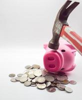 een stapel van roze varken munten aan het liegen Aan top een hand- Holding een hamer is beukende een roze varken. de concept van economisch depressie. inflatie, verlies foto
