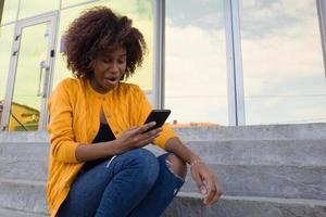 de gelukkige Afro-Amerikaanse vrouw op straat die aan de telefoon praat foto