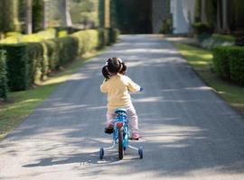 Aziatisch baby meisje kind aan het leren naar rijden fiets in de park tuin. onderwijs concept voor kind oefenen wielersport Bij park, baby sport concept. foto