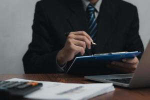 zakenman Holding pen handtekening document Aan klembord Bij bureau. bedrijf informatie verzekering advocaat en baan concept. foto