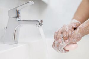 hygiëne. schoonmaak handen. het wassen handen met zeep onder de kraan met water betalen aarde. foto