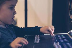 dichtbij omhoog van kind aanpassen volume Aan geluid menger in muziek- studio. foto