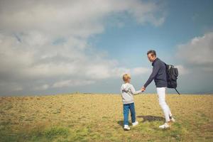 vader en zoon pratend terwijl uitgeven dag natuur. foto