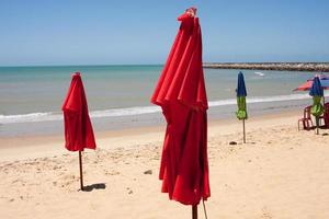 rood gevouwen paraplu's zit vast in de zanderig kustlijn Bij iracema strand in fortaleza, Brazilië foto