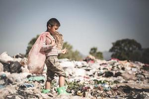 arm kinderen verzamelen vuilnis voor verkoop.en recycle hen in stortplaatsen, de leeft en levensstijlen van de arm, kind arbeid, armoede en milieu concepten foto