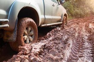 vuile offroad-auto, suv bedekt met modder op plattelandsweg, offroad-banden, offroad-reizen en rijconcept. foto