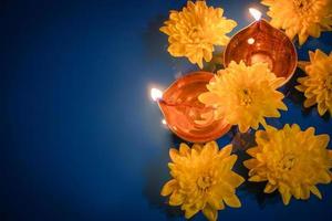 gelukkig divali. diya olie lampen en geel bloemen Aan blauw achtergrond. vieren de traditioneel Indisch vakantie van licht. foto