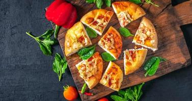 top visie van huis gemaakt pizza, groenten, ingrediënten Aan een zwart houten achtergrond. pizza is Koken in de houten hakken bord . pizza menu. foto