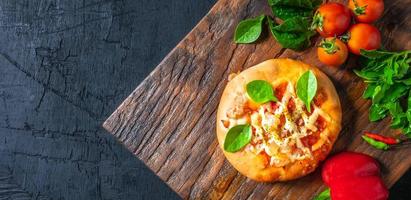 top visie van huis gemaakt pizza, groenten, ingrediënten Aan een zwart houten achtergrond. pizza is Koken in de houten hakken bord . pizza menu. foto