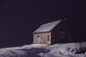 traditioneel Noors vissers hutten gedekt met sneeuw Bij nacht foto