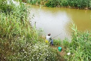 visser is visvangst Aan oever van de rivier foto