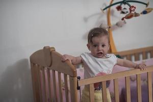 schattig weinig een jaar oud baby en maken eerste stappen in bed foto