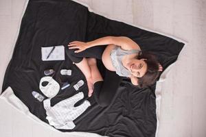 top visie van zwanger vrouw controle lijst van baby kleren foto