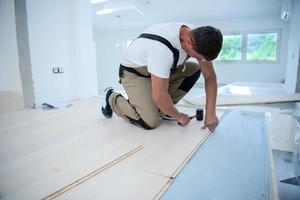 professionele werknemer die nieuwe gelamineerde houten vloer installeert foto