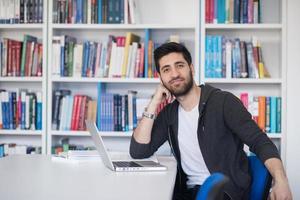 leerling in school- bibliotheek gebruik makend van laptop voor Onderzoek foto