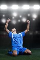 voetbal speler in voorkant van groot modern stadion met fakkels en lichten foto
