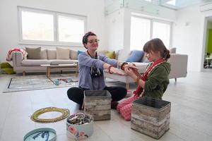 moeder en weinig meisje dochter spelen met sieraden Bij huis foto