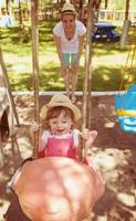 moeder en dochter swinging in de park foto