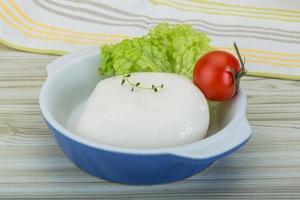 Mozzarella in een kom Aan houten achtergrond foto