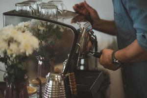 barista Mens cafe maken koffie voorbereiding onderhoud concept in restaurant. dichtbij omhoog hand- barista maken vers koffie met koffie machine in de cafe. maken vers koffie espresso. foto