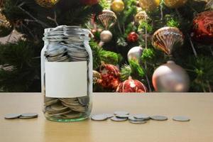 geld in de glazen fles met versierde kerstboom achtergrondvervaging foto