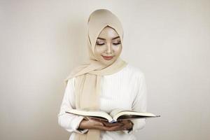 jonge aziatische moslimvrouw die lacht en de koran vasthoudt foto