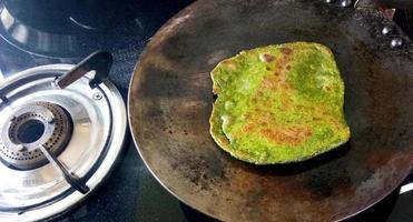 bereiding van palak paratha in pakistan, noord-india door het rollen van atta-deeg met aardappelpuree vulling met deegroller en gebraden. serveer met indisch bijgerecht dal makhani foto