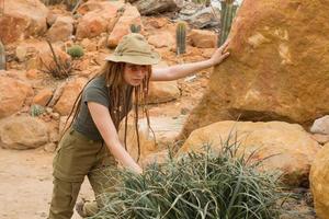 jonge mannelijke reiziger in woestijn, vrouwelijke wandelaar in cactustuin foto