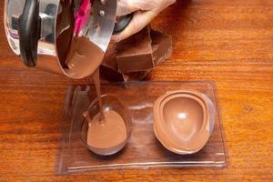 zelfgemaakte paaseifabriek. eierschaal maken van paasei met gesmolten chocolade en een vorm. foto