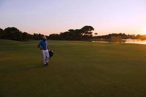 golfspeler wandelen en draag- golf zak Bij mooi zonsondergang foto