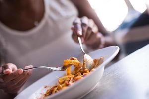 een jonge Afro-Amerikaanse vrouw die pasta eet foto