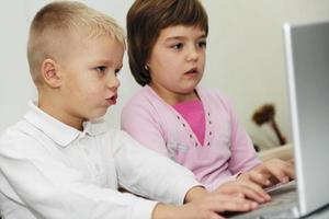 kinderen hebben plezier en spelen spelletjes op een laptopcomputer foto