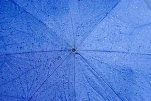 top visie achtergrond en structuur van regendruppels Aan blauw paraplu. foto