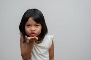 portret van een gelukkig en grappig Aziatisch kindmeisje op een witte achtergrond, een kind dat naar de camera kijkt. voorschoolse jongen droomt vol met energie en voelt zich gezond en goed concept foto