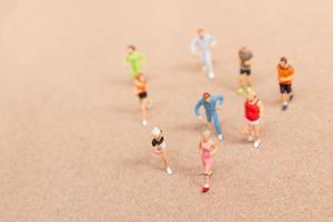 miniatuurmensen die sporten terwijl ze in een groep op het strand rennen foto