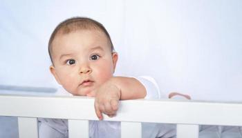 schattig portret van een baby in een wieg detailopname. een kind in wit kleren Aan wit ondergoed. tederheid en zorg, kinderen problemen. foto