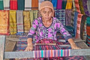 droevig dorp, lombok, Indonesië, juni 2021- een vrouw weeft garen naar worden gebruikt net zo sesek foto